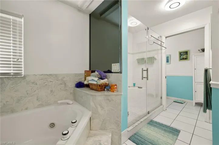 Bathroom featuring tile patterned flooring, a jetted tub, and a shower stall