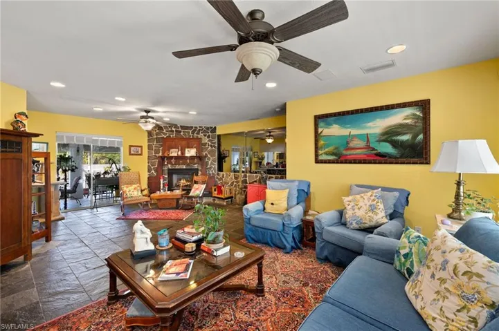 Living room featuring recessed lighting, visible vents, a stone fireplace, and stone tile floors