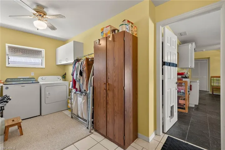 Laundry area with cabinet space, visible vents, separate washer and dryer, and light tile patterned flooring