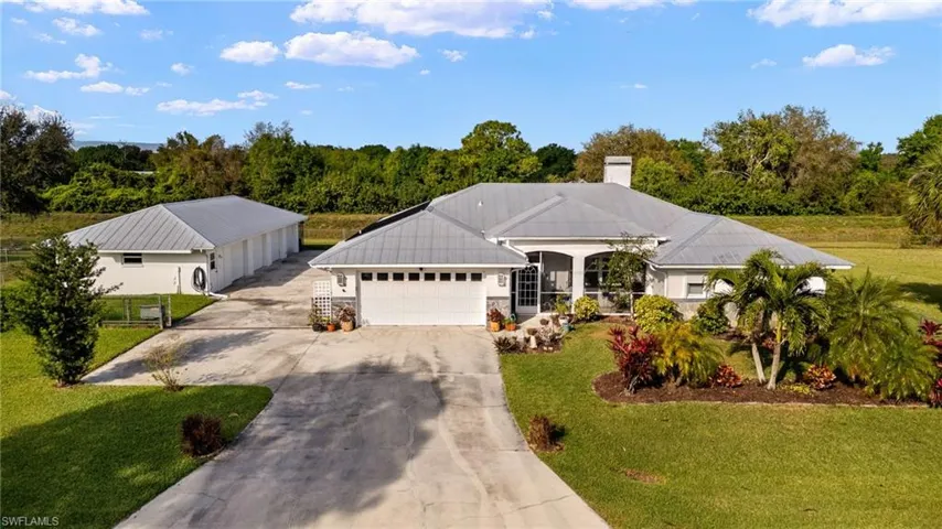 View of front facade with concrete driveway, a front lawn, a chimney, and an attached garage