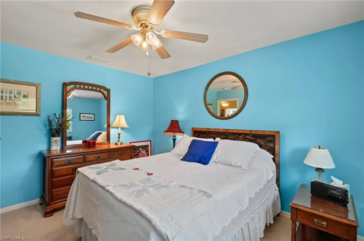 Bedroom with a ceiling fan, visible vents, light carpet, and baseboards