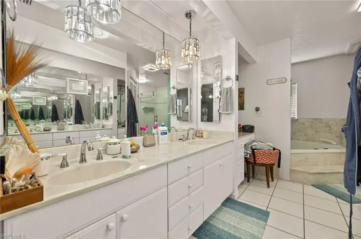 Bathroom featuring double vanity, a bath, a sink, and tile patterned floors