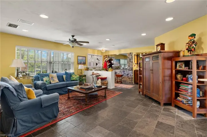 Living room featuring ceiling fan, visible vents, stone finish flooring, and recessed lighting