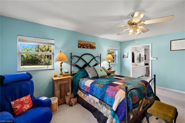 Carpeted bedroom with ensuite bath, a ceiling fan, and baseboards