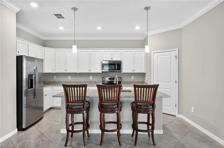 Kitchen featuring stainless steel appliances, white cabinets, crown molding, and light tile patterned floors