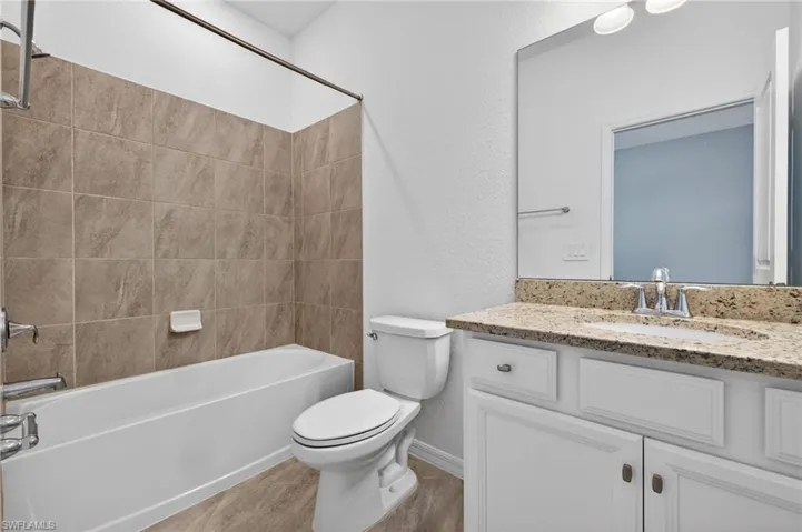 Bathroom featuring a textured wall, vanity, and shower / tub combination