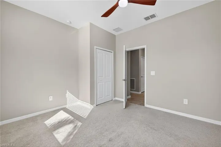 Unfurnished bedroom with light colored carpet, a ceiling fan, and a closet