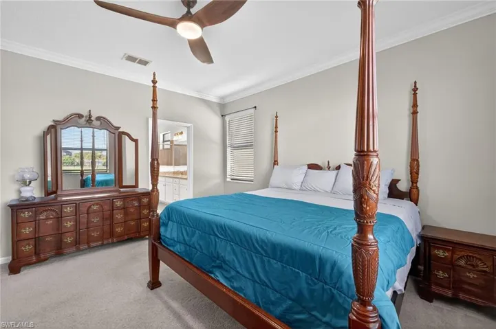 Bedroom featuring light colored carpet, multiple windows, a ceiling fan, and crown molding