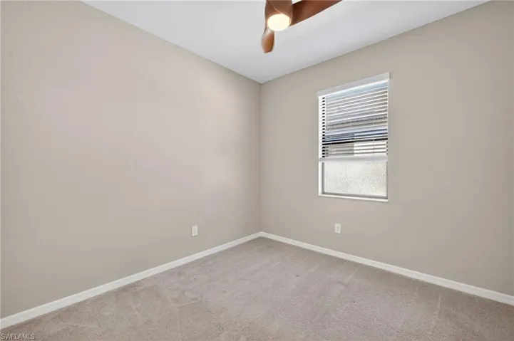 Unfurnished room featuring light carpet and a ceiling fan
