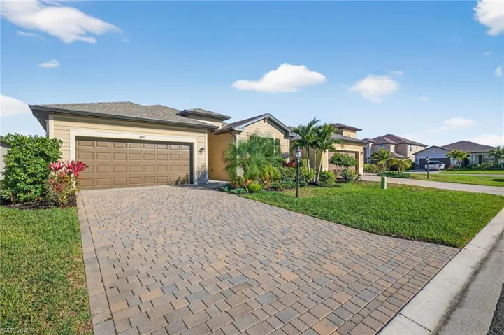 View of front of property featuring a front yard, decorative driveway, an attached garage, and a residential view