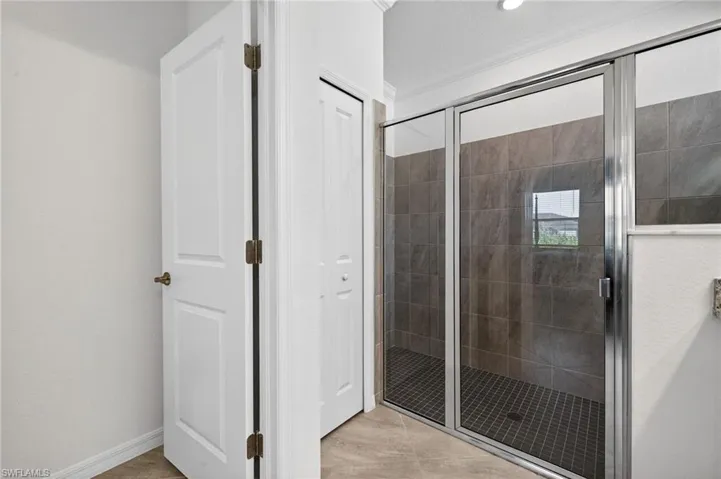 Bathroom featuring a stall shower, ornamental molding, light tile patterned flooring, and a closet