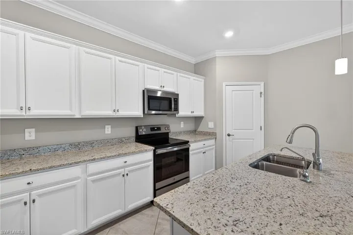 Kitchen with stainless steel appliances, white cabinetry, light stone countertops, crown molding, and pendant lighting