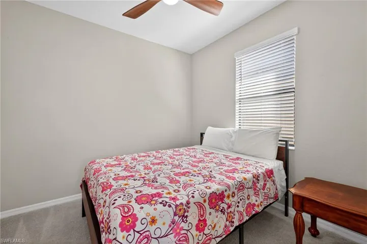 Bedroom featuring light colored carpet, ceiling fan, and vaulted ceiling