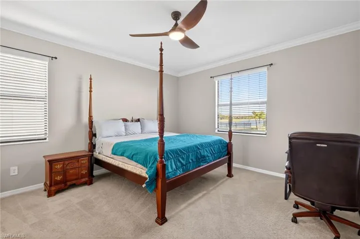 Bedroom with light colored carpet, crown molding, and a ceiling fan