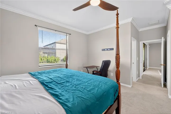 Bedroom featuring ornamental molding, light carpet, ceiling fan, and an office area