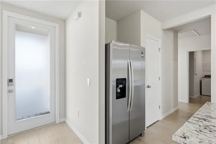 Stainless steel side-by-side refrigerator, white paneled doors, and light wood-finish flooring