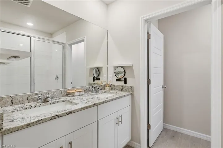 Dual vanity with a stone countertop, chrome hardware, and undermount sinks