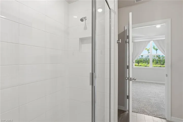 Shower enclosure featuring white subway tile, a recessed niche, and a chrome showerhead