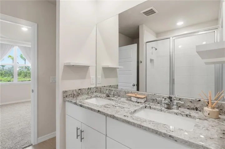 Bathroom featuring a double vanity with stone countertops, integrated sinks, and chrome fixtures
