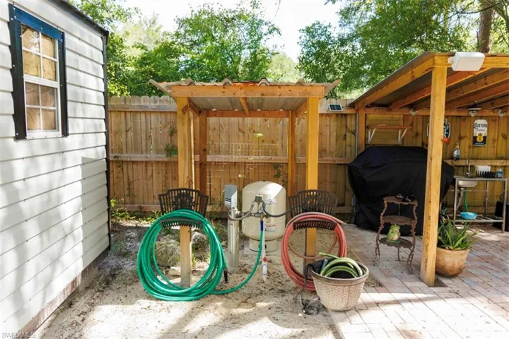 Outdoor utility area featuring a white horizontal siding structure and a wood privacy fence