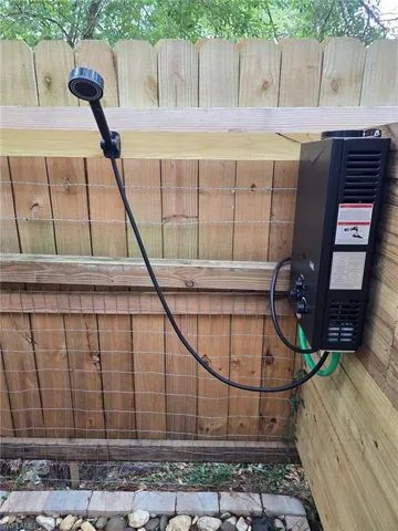 Outdoor shower system featuring a handheld showerhead and a wall-mounted water heater
