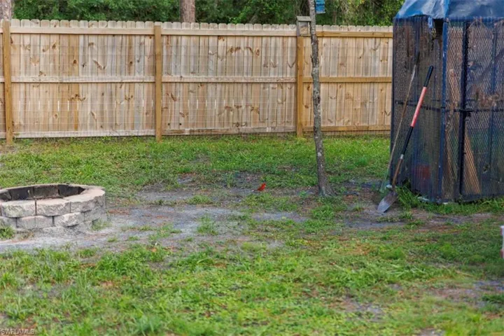 Backyard featuring a privacy fence, a stone-block fire pit, and a grassy area