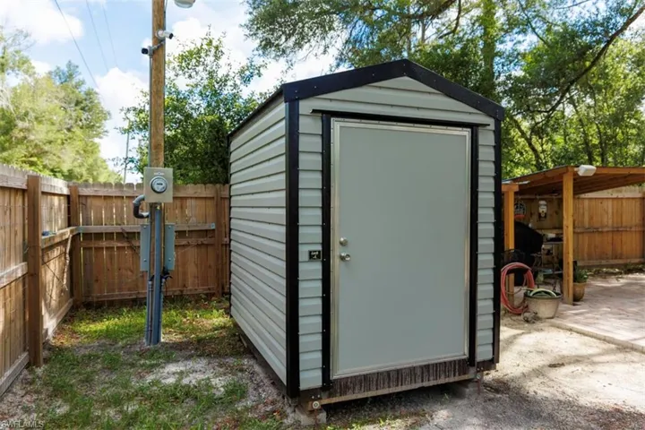 Utility shed with horizontal siding, a gabled roof, and a single entry door