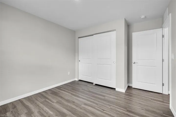 Unfurnished bedroom with wood finished floors and a closet