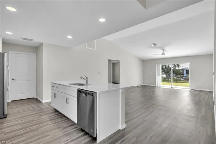 Kitchen featuring appliances with stainless steel finishes, open floor plan, white cabinetry, light wood-style flooring, and recessed lighting