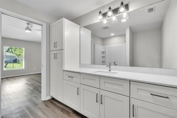 Bathroom featuring vanity, light wood-style flooring, and a shower stall
