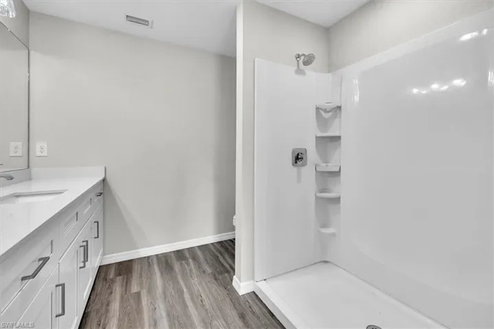 Bathroom with vanity, a stall shower, and light wood-type flooring