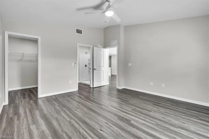 Unfurnished bedroom featuring vaulted ceiling, wood finished floors, a spacious closet, and ceiling fan