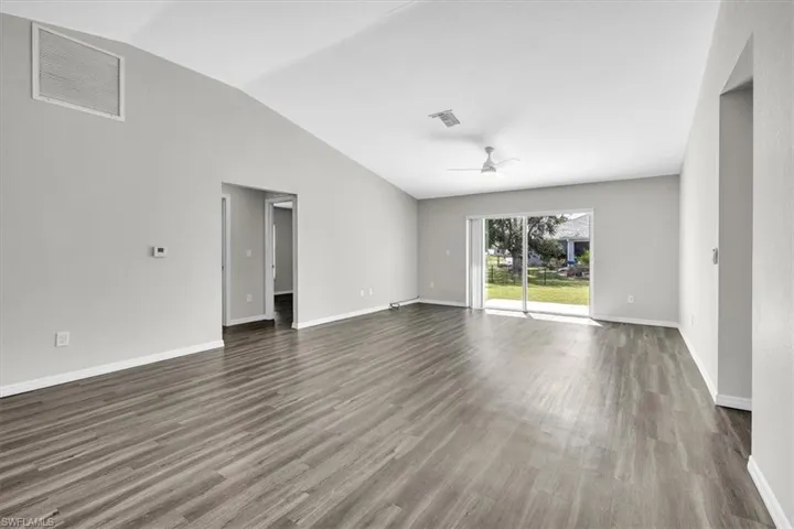 Spare room featuring wood finished floors, vaulted ceiling, and ceiling fan