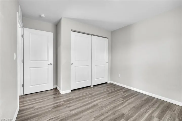 Unfurnished bedroom with wood finished floors and a closet