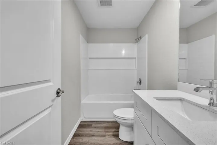 Full bathroom featuring vanity, shower / bath combination, and dark wood-style floors