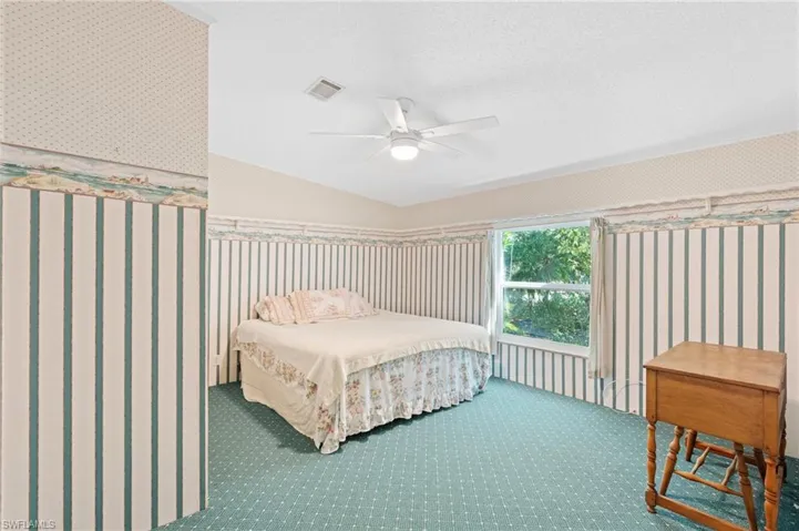 Bedroom with visible vents, a textured ceiling, carpet flooring, wallpapered walls, and ceiling fan