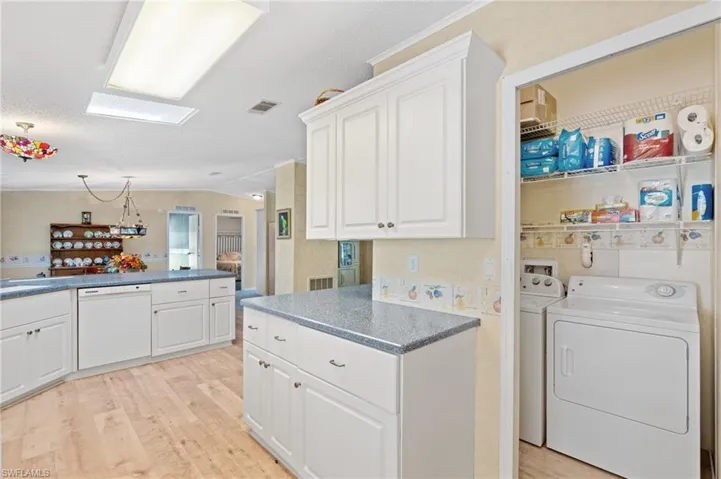 Laundry area with washing machine and clothes dryer, visible vents, light wood-type flooring, and a sink
