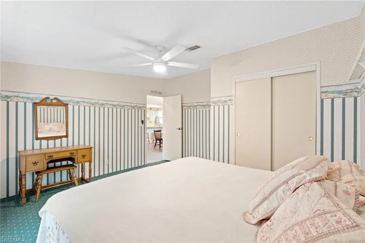 Bedroom with visible vents, carpet, and wallpapered walls