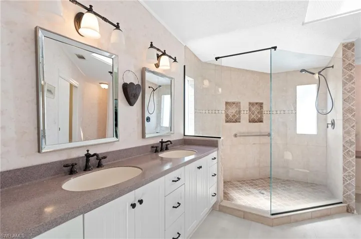 Bathroom with a textured ceiling, tiled shower, and a sink