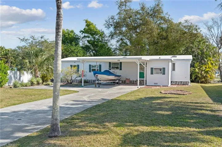 Manufactured / mobile home featuring a carport, crawl space, driveway, and a front yard