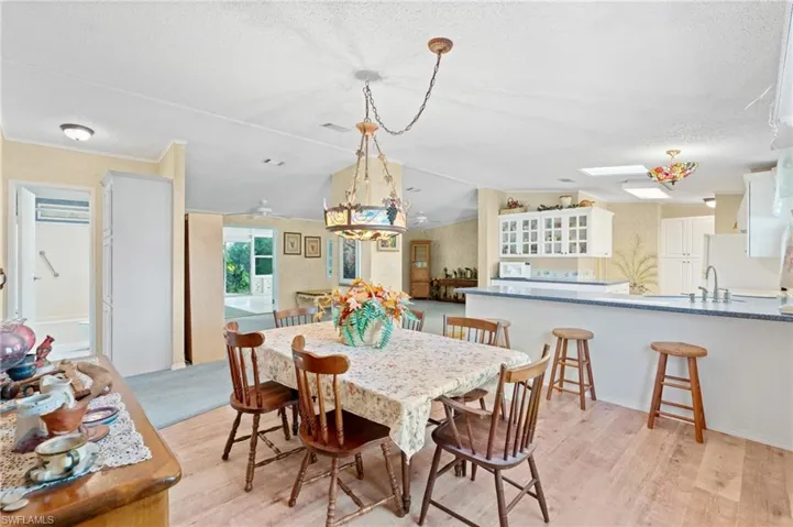 Dining area with a textured ceiling, a skylight, and light wood finished floors