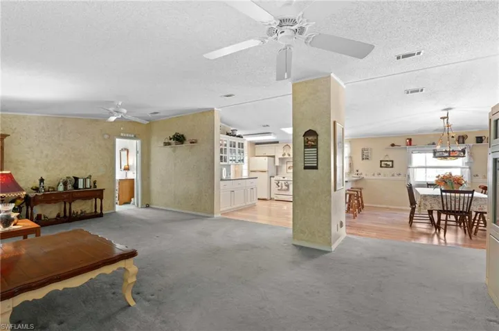 Living room featuring light carpet, visible vents, and a ceiling fan