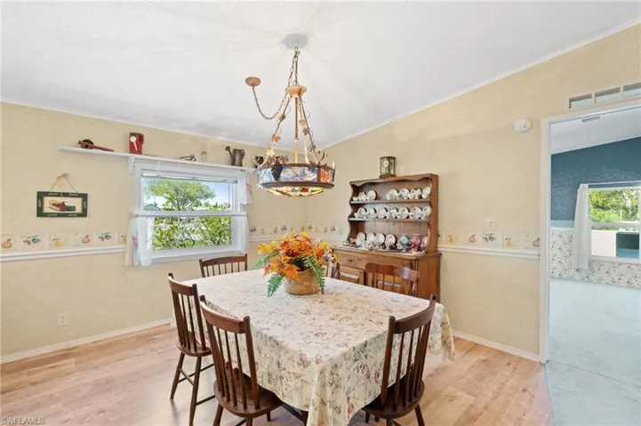 Dining space featuring visible vents, baseboards, light wood-style floors, and crown molding