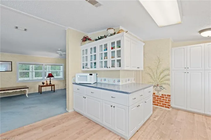 Kitchen featuring white microwave, visible vents, and light wood-type flooring