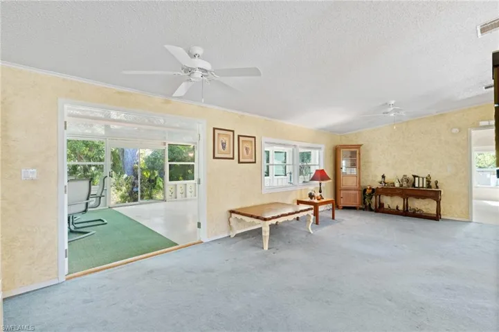 Miscellaneous room featuring visible vents, carpet floors, a textured wall, a textured ceiling, and a ceiling fan