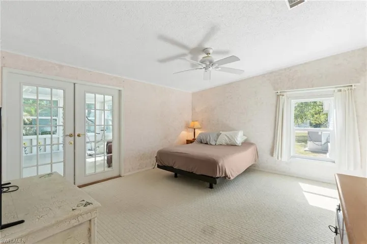 Carpeted bedroom featuring visible vents, french doors, a textured ceiling, crown molding, and access to outside