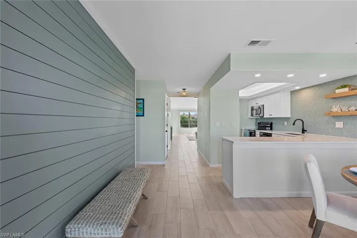 Kitchen featuring sink, a raised ceiling, kitchen peninsula, white cabinets, and appliances with stainless steel finishes