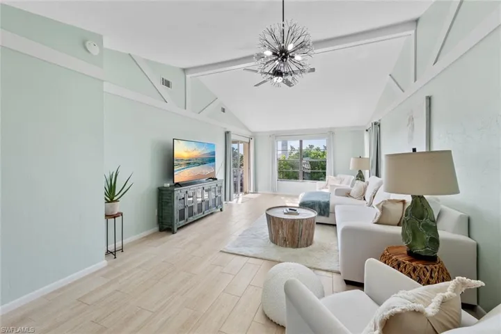 Living room featuring a notable chandelier, light hardwood / wood-style floors, and vaulted ceiling