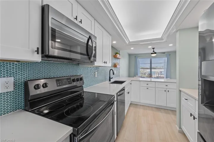 Kitchen with tasteful backsplash, white cabinetry, sink, and stainless steel appliances