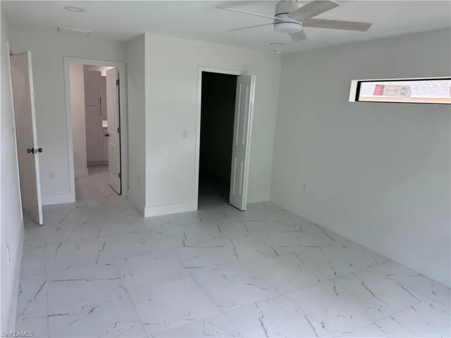 Unfurnished bedroom featuring light tile patterned flooring, a spacious closet, ceiling fan, and a closet